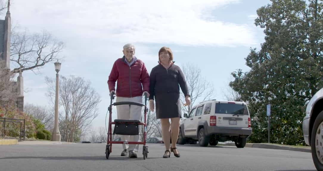 Older man walking with a support doctor.